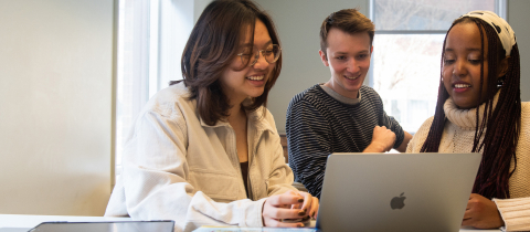 3 students sitting down together in front of a laptop