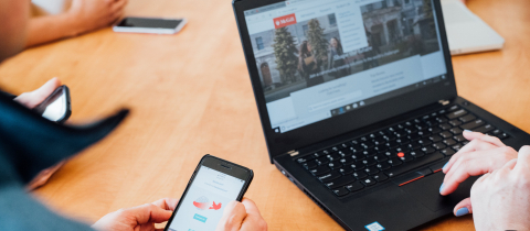 People holding a laptop and a mobile phone at a table, both displaying McGill websites
