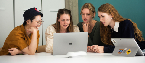 4 students sitting down together in front of a laptop