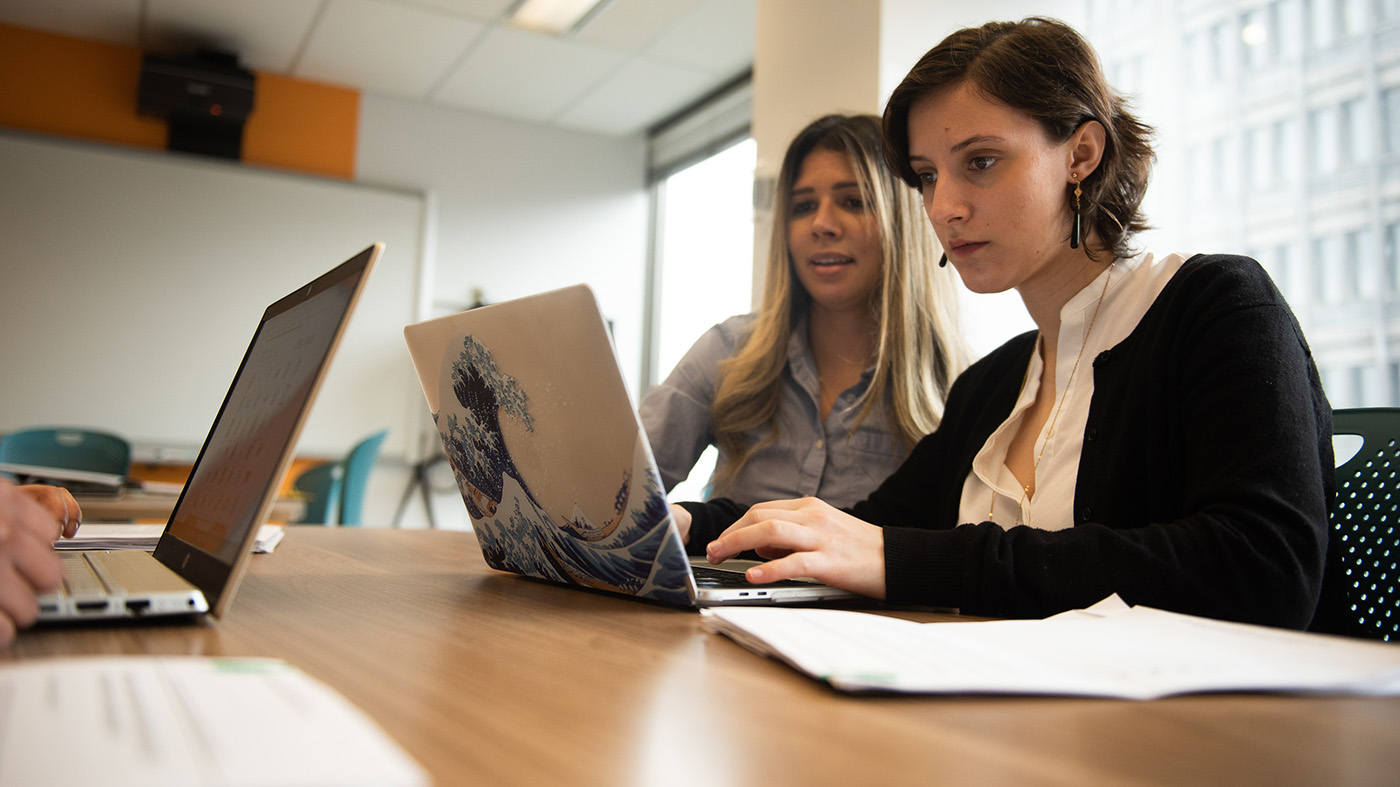 Two students sitting in front of a laptop