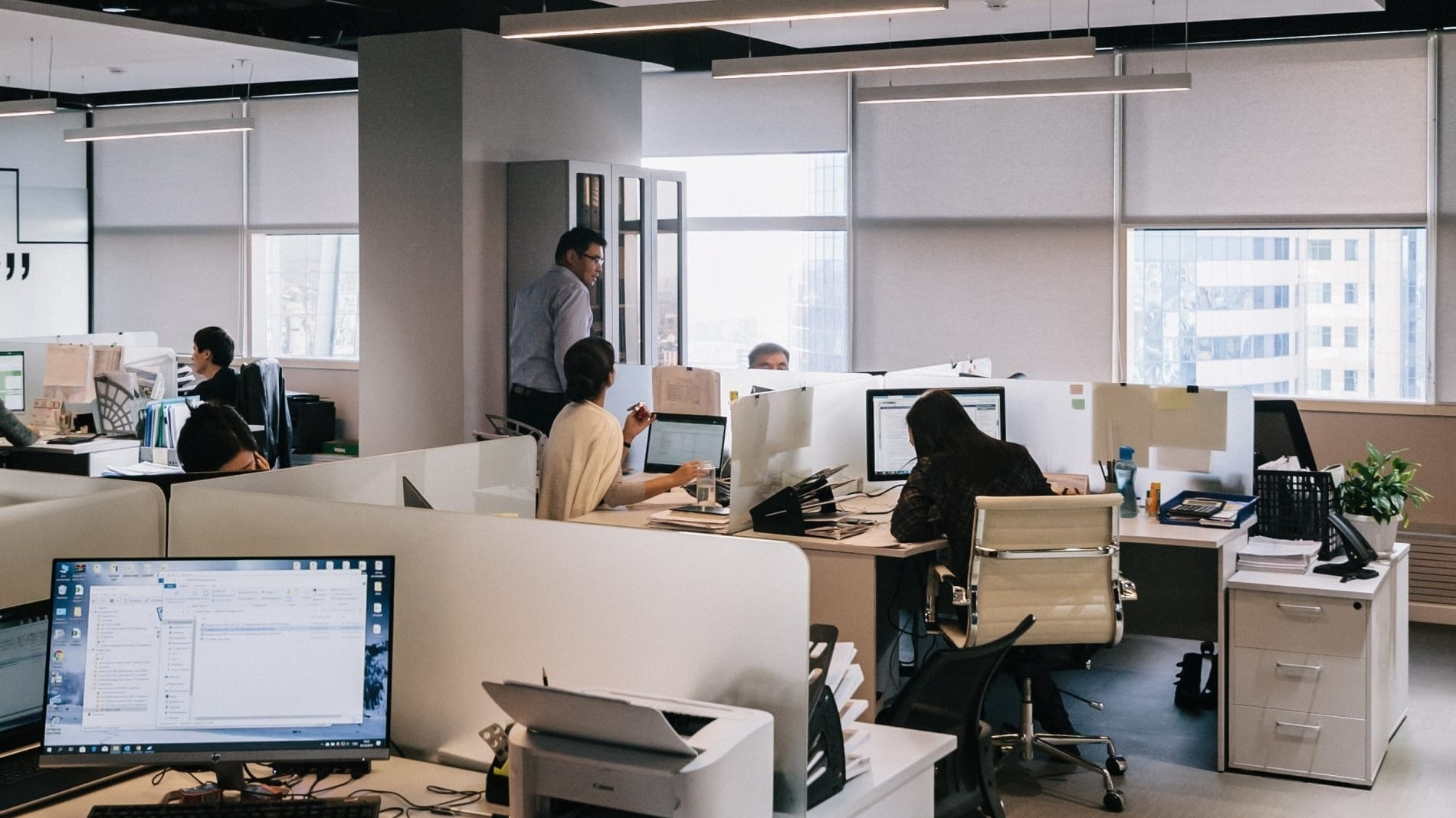 White themed office with workers and computers in cubicles