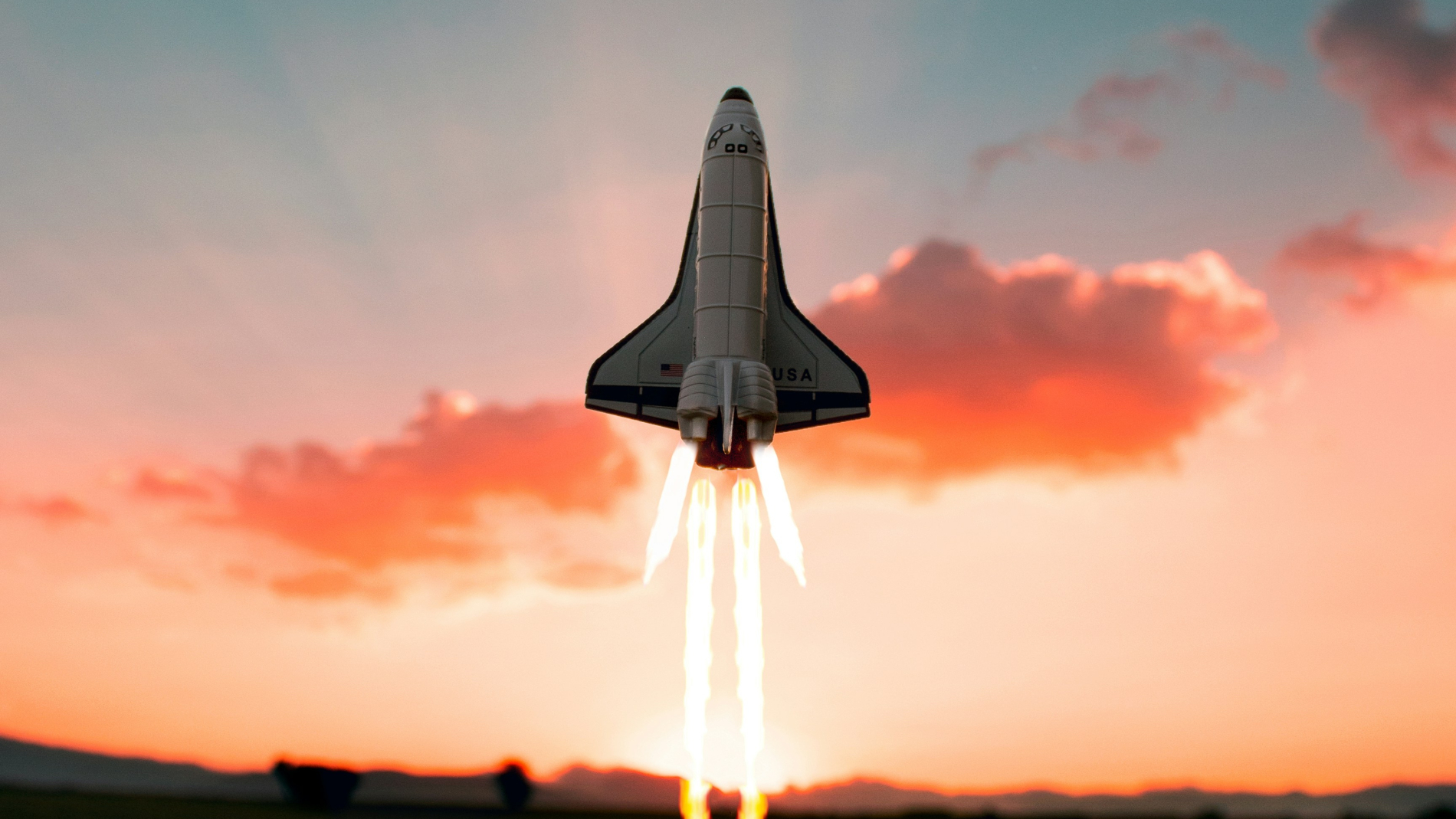 Toy rocket launch with sunset in slightly cloudy sky as background
