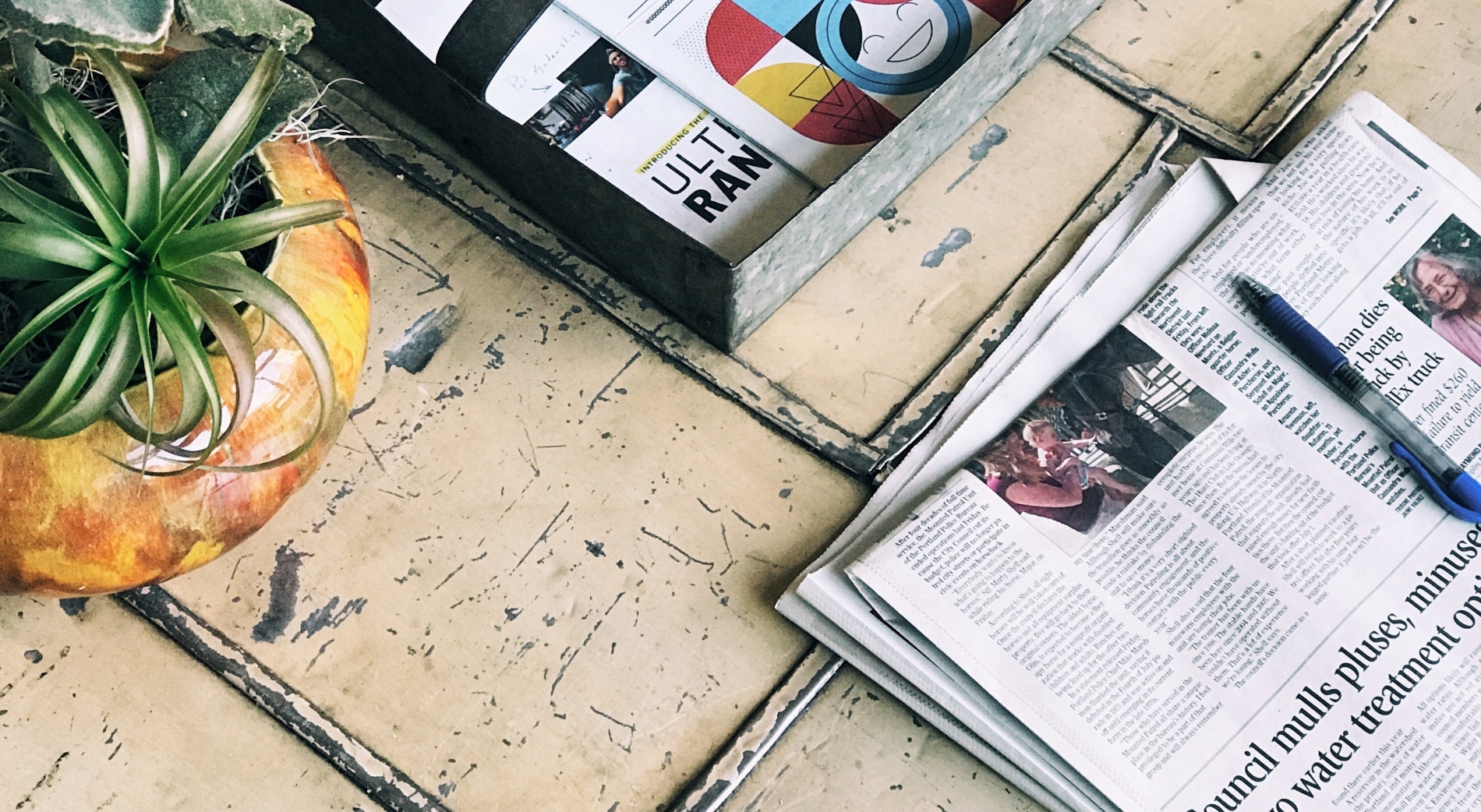 Newspaper beside a metal basket holding more newspapers on the ground