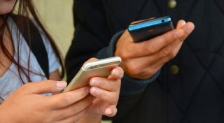 two people's hands holding cell phones