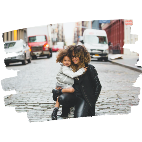 A mother embraces her son while posing for a photo in the street