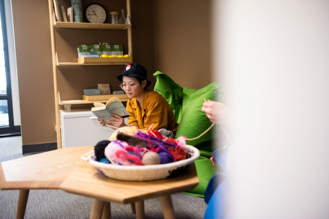 A student sits, reading, in the lounge area of the Healthy Living Annex