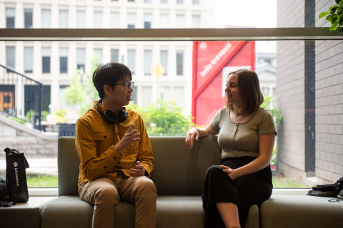 Two students seated, conversing, in the Brown Student Services building lobby