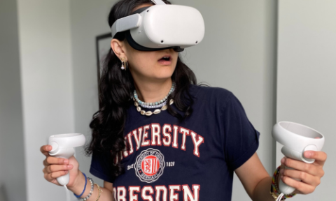 A student wears a virtual reality headset while holding the controllers