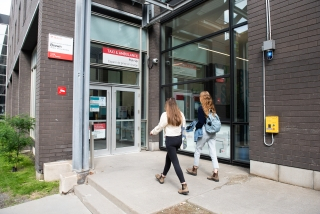 Two students walk towards the entrance to the Student Wellness Hub, off of Dr. Penfield Avenue.